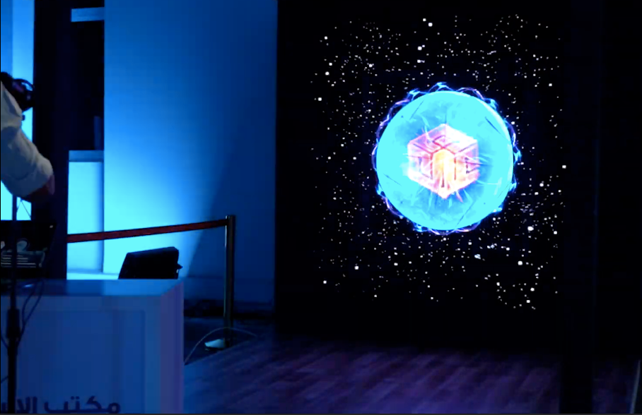 A glowing blue holographic sphere with a digital core displayed on an AI-linked screen at the Oman Innovation Festival, demonstrating immersive AI-driven technology