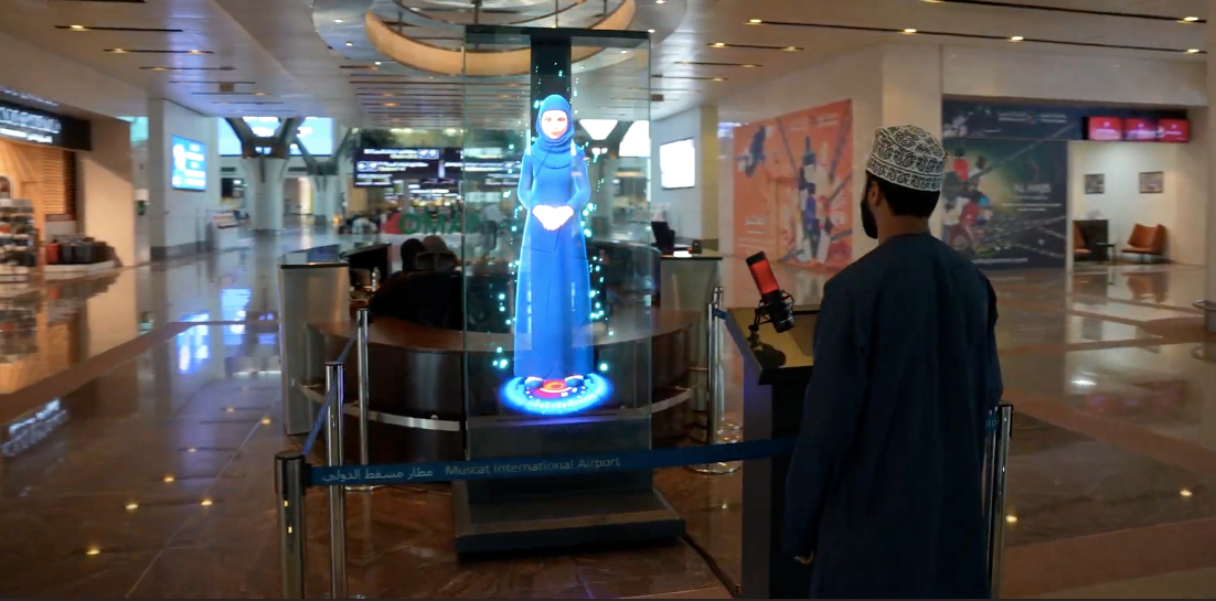 An Omani visitor interacts with "Noura," Oman's first AI-powered holographic assistant, displayed as a life-sized hologram at Muscat International Airport